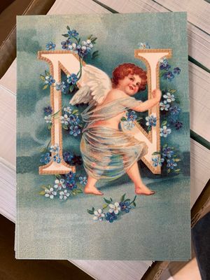 a card with a picture of an angel holding a letter n