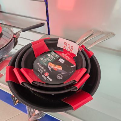 plusieurs casseroles et poêles exposées dans un magasin, accompagnées d'étiquettes de prix