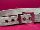 a close up of a belt with a metal buckle on a pink background