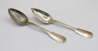 two silver spoons sitting on top of a white table next to each other