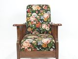La chaise est en bois et son assise est recouverte d'un tissu à motifs floraux.