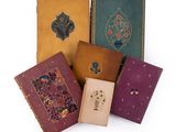 four old books are lined up in a row on a white surface
