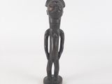 wooden statue of a man with a hat on his head and hands on his hips