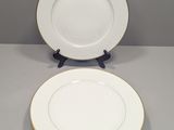 deux assiettes blanches aux bords dorés reposent sur une surface grise