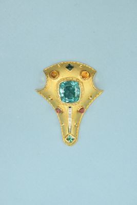 a gold brooch with a green stone in it