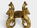 an image of a gold colored table with two horses on top of it
