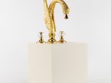 une image représentant une statue d'oiseau doré posée sur un socle blanc