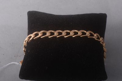 a close up of a gold chain bracelet on a black pillow