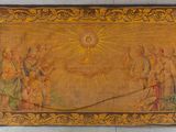 an old tapestry hanging on a wall with a sun above it