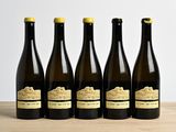 six bottles of wine are lined up on a wooden table