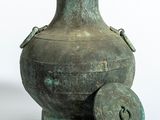 un vase vert muni d'un couvercle, posé sur une surface blanche