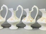 quatre vases blancs ornés de motifs dorés, posés sur une table