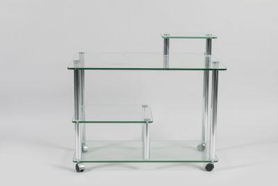 une table en verre transparent avec deux étagères, montée sur roulettes