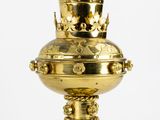a gold vase with a crown on it sitting on a table