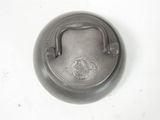 a metal pot with a handle on a white surface