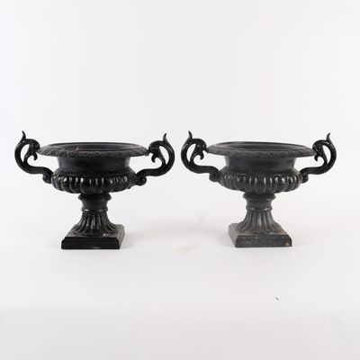 deux urnes noires posées l'une à côté de l'autre sur une surface blanche