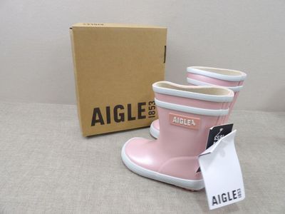 une paire de bottes de pluie roses posée à côté d'une boîte