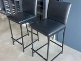 pair of black leather bar stools with metal legs