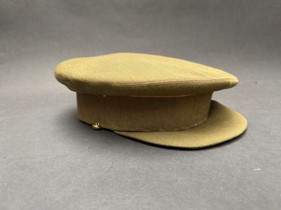 Le chapeau est de couleur beige et comporte un bouton sur le côté.