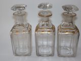 trois bouteilles en verre vides posées les unes à côté des autres sur une table
