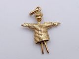 a gold charm with a doll on it on a white surface