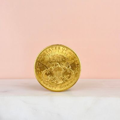 gold coin sitting on a marble surface against a pink background