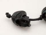two black skulls on a string on a white surface