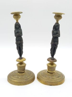 paire de bougeoirs anciens en laiton ornés de figurines représentant un homme et une femme