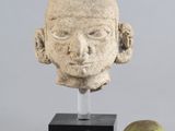 sculpture représentant une tête d'homme à côté d'une poire posée sur un socle