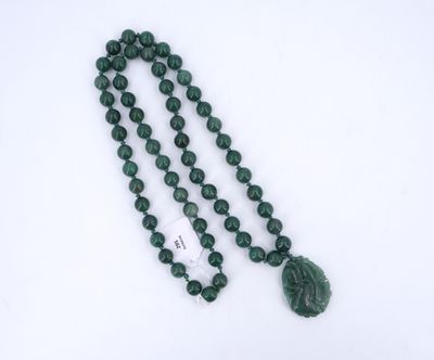 un gros plan sur un collier de perles vertes orné d'un pendentif en forme de feuille