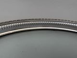 an oval silver tray with a decorative design on the rim