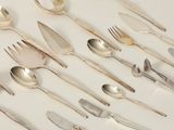un grand nombre de cuillères et de fourchettes disposées sur la table