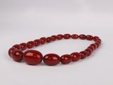 a red beaded necklace with two round beads on a white background