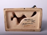 a small ceramic sculpture of a bird on a shelf