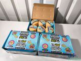 three boxes of doughnuts on a table with a box of doughnuts in the background
