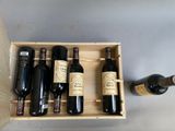 four bottles of wine in a wooden box next to a bottle of wine