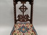 une chaise ancienne en bois dont l'assise est recouverte d'un tissu coloré sur fond blanc