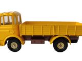 un petit camion jaune posé sur une surface blanche