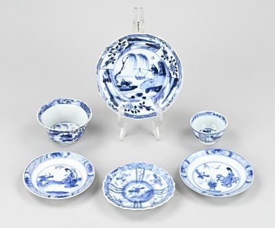 des assiettes, tasses et soucoupes en porcelaine bleue et blanche, présentées sur un présentoir