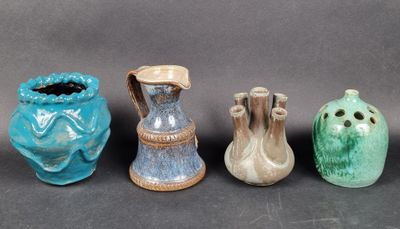 quatre vases de couleurs différentes sont alignés sur une surface noire