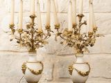 deux vases blancs et dorés avec des bougies posés sur une table