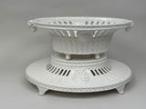 a large white bowl on a stand on a gray surface