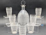 six verres et une carafe posés sur une table