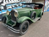 an old green car parked in front of a building