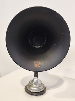 une enceinte noire posée sur un pied, sur une table