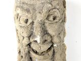 une sculpture en pierre représentant un visage sur une surface blanche