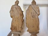 two statues on a table with a clock in the background