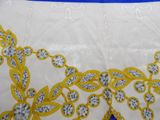 yellow and white embroidered tablecloth with a blue border on a table