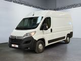 La camionnette blanche est garée dans une grande pièce au sol gris.