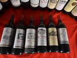 several bottles of wine are lined up on a red table cloth